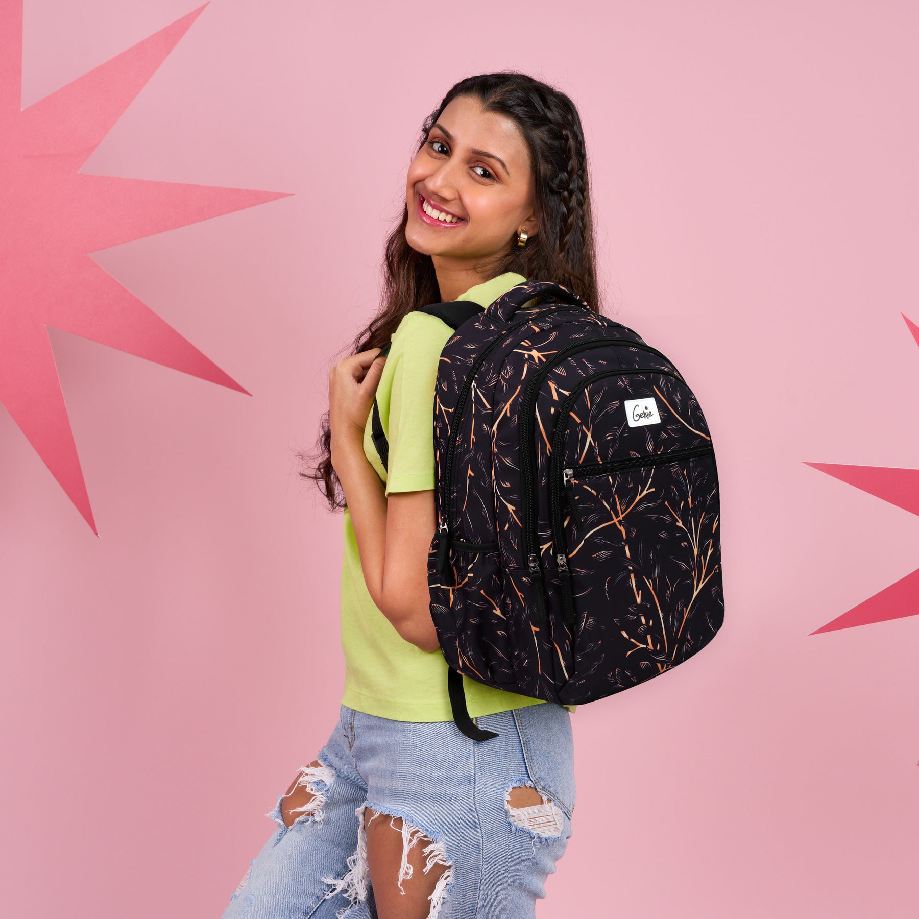 A smiling woman wearing a black backpack with orange branch pattern
